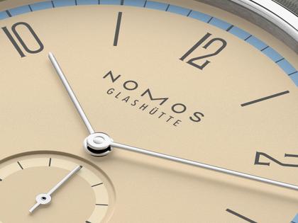 Nomos Glashütte Tangente 38 Datum "175 Years Watchmaking - Ariel" Handaufzug Edelstahl sandfarbenes Zifferblatt graues Textilband Glasboden – Herrenuhren Uhr mit Datum aus Edelstahl. Das Gehäuse ist rund und silber. Das Textilarmband ist grau. Das Zifferblatt ist arabisch Index und beige. – Ansicht 5