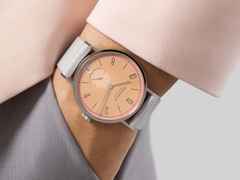 Nomos Glashütte Tangente 38 Datum "175 Years Watchmaking - Pastell" Handaufzug Edelstahl korallfarbenes Zifferblatt graues Textilband Glasboden – Herrenuhren Uhr mit Datum aus Edelstahl. Das Gehäuse ist rund und silber. Das Textilarmband ist grau. Das Zifferblatt ist arabisch Index und orange. – Ansicht 7
