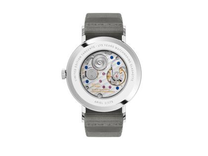 Nomos Glashütte Tangente 38 Datum "175 Years Watchmaking - Ariel" Handaufzug Edelstahl sandfarbenes Zifferblatt graues Textilband Glasboden – Herrenuhren Uhr mit Datum aus Edelstahl. Das Gehäuse ist rund und silber. Das Textilarmband ist grau. Das Zifferblatt ist arabisch Index und beige. – Ansicht 2