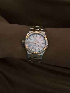 Maurice Lacroix Aikon Quarz Edelstahl 35mm weißes Zifferblatt zweifarbiges Metallband – Damenuhren Uhr mit Datum aus Edelstahl, PVD beschichtet und vergoldet. Das Gehäuse ist rund und silber-roségold. Das vergoldetes Edelstahlarmband ist silber-roségold. Das Zifferblatt ist ein Index in weiß. – Ansicht 2