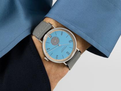 Nomos Glashütte Tangente 38 Datum "175 Years Watchmaking - Delfin" Handaufzug Edelstahl blaues Zifferblatt graues Textilband Glasboden – Herrenuhren Uhr mit Datum aus Edelstahl. Das Gehäuse ist rund und silber. Das Textilarmband ist grau. Das Zifferblatt ist arabisch Index und blau. – Ansicht 7