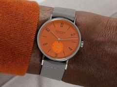Nomos Glashütte Tangente 38 Datum "175 Years Watchmaking - Poporange" Handaufzug Edelstahl orangenes Zifferblatt graues Textilband Glasboden – Herrenuhren Uhr mit Datum aus Edelstahl. Das Gehäuse ist rund und silber. Das Textilarmband ist grau. Das Zifferblatt ist arabisch Index und orange. – Ansicht 8