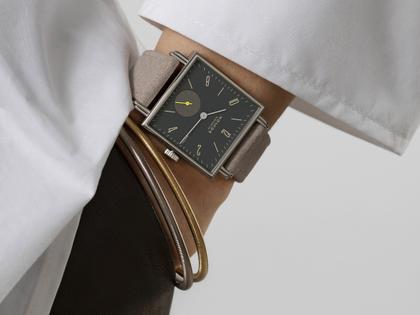 Nomos Glashütte Tetra Origins Basalt Handaufzug Edelstahl 29,5mm schwarzes Zifferblatt graues Lederband Stahlboden – Damenuhren Uhr ohne Datum aus Edelstahl und Leder. Das Gehäuse ist quadratisch und silber. Das Lederarmband ist grau. Das Zifferblatt ist arabisch Index und schwarz. – Ansicht 11