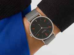 Nomos Glashütte Tangente 38 Datum "175 Years Watchmaking - Dunkelbunt" Handaufzug Edelstahl schwarzes Zifferblatt graues Textilband Glasboden – Herrenuhren Uhr mit Datum aus Edelstahl. Das Gehäuse ist rund und silber. Das Textilarmband ist grau. Das Zifferblatt ist arabisch Index und schwarz. – Ansicht 7