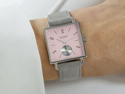 Nomos Glashütte Tetra Die Wildentschlossene Handaufzug Edelstahl 29mm rosafarbenes Zifferblatt graues Veloursband Glasboden – Damenuhren Uhr ohne Datum aus Edelstahl und Leder. Das Gehäuse ist quadratisch und silber. Das Lederarmband ist grau. Das Zifferblatt ist arabisch Index und rosa. – Ansicht 4