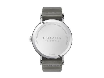 Nomos Glashütte Tangente 38 – 50 ans de Médecins Sans Frontières Limited Edition Handaufzug Edelstahl 38mm weißes Zifferblatt graues Textilband Stahlboden – Herrenuhren Uhr ohne Datum aus Edelstahl und Leder. Das Gehäuse ist rund und silber. Das Textilarmband ist schwarz. Das Zifferblatt ist arabisch Index und weiß. – Ansicht 2