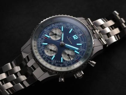 Sinn Spezialuhren 903 Ti II Jubiläum Navigationschronograph Automatik Titan 41mm blaues Zifferblatt braunes Lederband und Titanband limitiert – Herrenuhren Chronograph aus Titan. Das Gehäuse ist rund und grau. Das Lederarmband ist braun. Das Zifferblatt ist arabisch Index und blau. – Ansicht 9