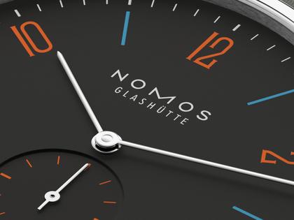 Nomos Glashütte Tangente 38 Datum "175 Years Watchmaking - Dunkelbunt" Handaufzug Edelstahl schwarzes Zifferblatt graues Textilband Glasboden – Herrenuhren Uhr mit Datum aus Edelstahl. Das Gehäuse ist rund und silber. Das Textilarmband ist grau. Das Zifferblatt ist arabisch Index und schwarz. – Ansicht 5