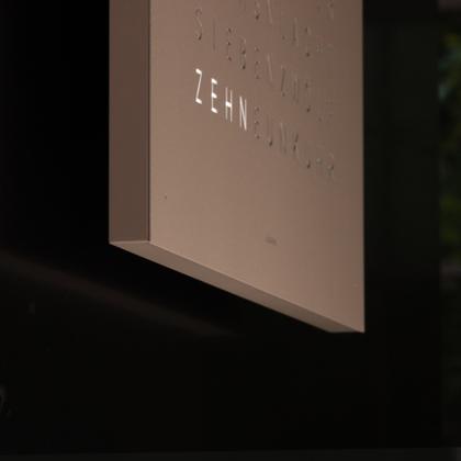 Qlocktwo Earth 45 Hazelnut Monochrome Edition – Großuhren Wanduhr aus . Das Gehäuse ist quadratisch und weiß. Das Zifferblatt ist digital und grau. – Ansicht 4