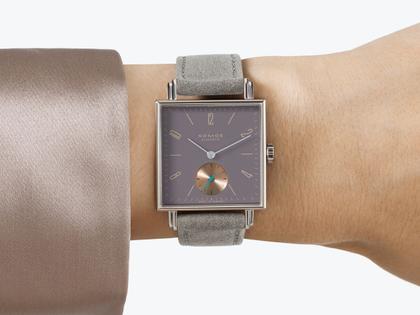 Nomos Glashütte Tetra Die Fuchsteufelswilde Handaufzug Edelstahl 29mm violettes Zifferblatt graues Veloursband Glasboden – Damenuhren Uhr ohne Datum aus Edelstahl und Leder. Das Gehäuse ist quadratisch und silber. Das Lederarmband ist grau. Das Zifferblatt ist arabisch Index und lila. – Ansicht 4