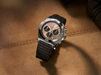 Breitling Chronomat B01 42 Automatik Edelstahl braunes Zifferblatt schwarzes Kautschukband – Herrenuhren Chronograph aus Edelstahl. Das Gehäuse ist rund und silber. Das Kautschuk / Kunststoff / Silikon Armband ist schwarz. Das Zifferblatt ist ein Index in bronze. – Ansicht 3
