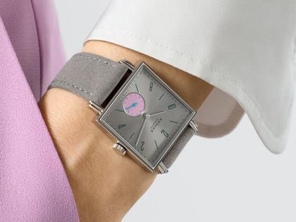 Nomos Glashütte Tetra Die Unerreichbare Handaufzug Edelstahl 29mm silberfarbenes Zifferblatt graues Veloursband Glasboden – Damenuhren Uhr ohne Datum aus Edelstahl und Leder. Das Gehäuse ist quadratisch und silber. Das Lederarmband ist grau. Das Zifferblatt ist arabisch Index und silber. – Ansicht 4