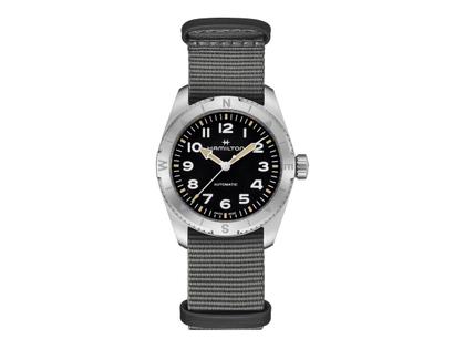 Hamilton Khaki Field Expedition Automatik Edelstahl 37mm schwarzes Zifferblatt graues Textilband – Herrenuhren Uhr ohne Datum aus Edelstahl. Das Gehäuse ist rund und silber. Das Textilarmband ist grau. Das Zifferblatt ist ein Index in schwarz.