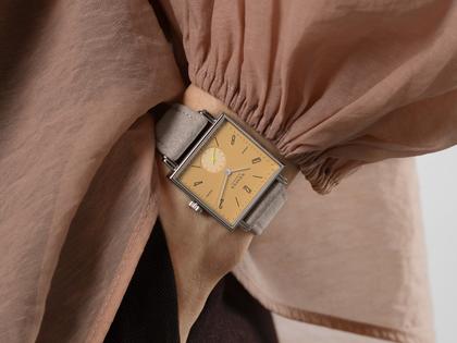 Nomos Glashütte Tetra Origins Ochra Handaufzug Edelstahl 29,5mm gelbes Zifferblatt graues Lederband Glasboden – Damenuhren Uhr ohne Datum aus Edelstahl und Leder. Das Gehäuse ist quadratisch und silber. Das Lederarmband ist grau. Das Zifferblatt ist arabisch Index und gelb. – Ansicht 12