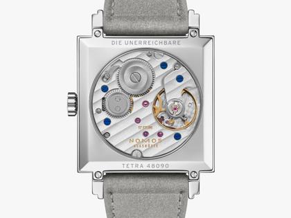 Nomos Glashütte Tetra Die Unerreichbare Handaufzug Edelstahl 29mm silberfarbenes Zifferblatt graues Veloursband Glasboden – Damenuhren Uhr ohne Datum aus Edelstahl und Leder. Das Gehäuse ist quadratisch und silber. Das Lederarmband ist grau. Das Zifferblatt ist arabisch Index und silber. – Ansicht 2