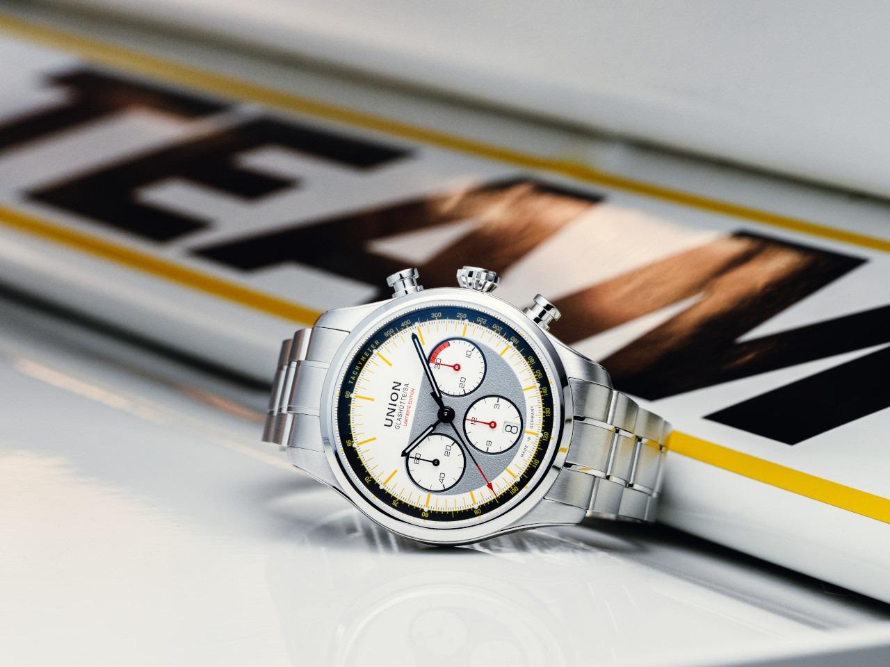 Union Glashütte Belisar Chronograph Silvretta Classic 2026 Limitierte Edition Automatik Edelstahl 44mm beiges Zifferblatt gelbes Textilband schwarzes Lederband und Metallband – Herrenuhren Chronograph aus Edelstahl und Leder. Das Gehäuse ist rund und silber. Das Textilarmband ist gelb. Das Zifferblatt ist ein Index in beige. – Ansicht 11