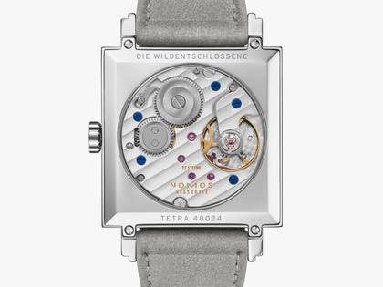 Nomos Glashütte Tetra Die Wildentschlossene Handaufzug Edelstahl 29mm rosafarbenes Zifferblatt graues Veloursband Glasboden – Damenuhren Uhr ohne Datum aus Edelstahl und Leder. Das Gehäuse ist quadratisch und silber. Das Lederarmband ist grau. Das Zifferblatt ist arabisch Index und rosa. – Ansicht 2