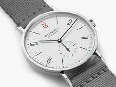Nomos Glashütte Tangente 38 – 50 ans de Médecins Sans Frontières Limited Edition Handaufzug Edelstahl 38mm weißes Zifferblatt graues Textilband Stahlboden – Herrenuhren Uhr ohne Datum aus Edelstahl und Leder. Das Gehäuse ist rund und silber. Das Textilarmband ist schwarz. Das Zifferblatt ist arabisch Index und weiß. – Ansicht 3