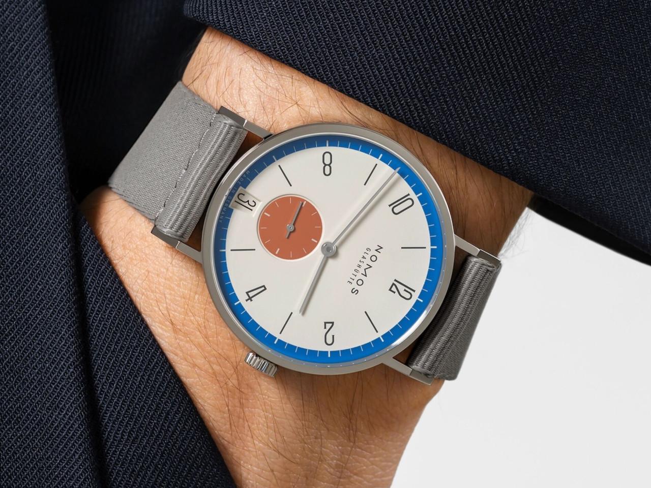 Nomos Glashütte Tangente 38 Datum "175 Years Watchmaking - Zirkus" Handaufzug Edelstahl cremeweißes Zifferblatt graues Textilband Glasboden – Herrenuhren Uhr mit Datum aus Edelstahl. Das Gehäuse ist rund und silber. Das Textilarmband ist grau. Das Zifferblatt ist arabisch Index und beige. – Ansicht 7