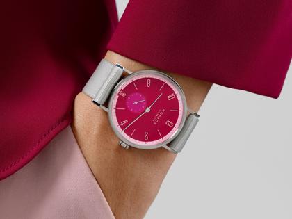 Nomos Glashütte Tangente 38 Datum "175 Years Watchmaking - Chili" Handaufzug Edelstahl pinkes Zifferblatt graues Textilband Glasboden – Herrenuhren Uhr mit Datum aus Edelstahl. Das Gehäuse ist rund und silber. Das Textilarmband ist grau. Das Zifferblatt ist arabisch Index und pink. – Ansicht 7