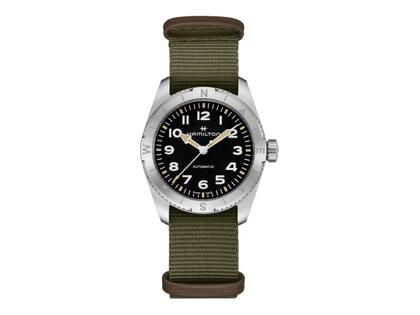 Hamilton Khaki Field Expedition Automatik Edelstahl 37mm schwarzes Zifferblatt olivgrünes Textilband – Herrenuhren Uhr ohne Datum aus Edelstahl. Das Gehäuse ist rund und silber. Das Textilarmband ist grün. Das Zifferblatt ist ein Index in schwarz.