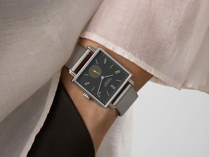 Nomos Glashütte Tetra Origins Basalt Handaufzug Edelstahl 29,5mm schwarzes Zifferblatt graues Lederband Stahlboden – Damenuhren Uhr ohne Datum aus Edelstahl und Leder. Das Gehäuse ist quadratisch und silber. Das Lederarmband ist grau. Das Zifferblatt ist arabisch Index und schwarz. – Ansicht 10