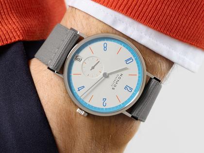 Nomos Glashütte Tangente 38 Datum "175 Years Watchmaking - Peace" Handaufzug Edelstahl cremeweißes Zifferblatt graues Textilband Glasboden – Herrenuhren Uhr mit Datum aus Edelstahl. Das Gehäuse ist rund und silber. Das Textilarmband ist grau. Das Zifferblatt ist arabisch Index und beige. – Ansicht 7
