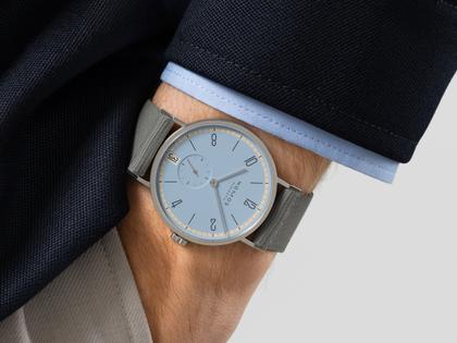 Nomos Glashütte Tangente 38 Datum "175 Years Watchmaking - Frostblau" Handaufzug Edelstahl eisblaues Zifferblatt graues Textilband Glasboden – Herrenuhren Uhr mit Datum aus Edelstahl. Das Gehäuse ist rund und silber. Das Textilarmband ist grau. Das Zifferblatt ist arabisch Index und blau. – Ansicht 6