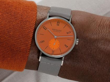 Nomos Glashütte Tangente 38 Datum "175 Years Watchmaking - Poporange" Handaufzug Edelstahl orangenes Zifferblatt graues Textilband Glasboden – Herrenuhren Uhr mit Datum aus Edelstahl. Das Gehäuse ist rund und silber. Das Textilarmband ist grau. Das Zifferblatt ist arabisch Index und orange. – Ansicht 8
