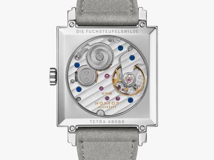Nomos Glashütte Tetra Die Fuchsteufelswilde Handaufzug Edelstahl 29mm violettes Zifferblatt graues Veloursband Glasboden – Damenuhren Uhr ohne Datum aus Edelstahl und Leder. Das Gehäuse ist quadratisch und silber. Das Lederarmband ist grau. Das Zifferblatt ist arabisch Index und lila. – Ansicht 2