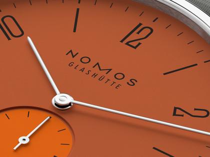 Nomos Glashütte Tangente 38 Datum "175 Years Watchmaking - Poporange" Handaufzug Edelstahl orangenes Zifferblatt graues Textilband Glasboden – Herrenuhren Uhr mit Datum aus Edelstahl. Das Gehäuse ist rund und silber. Das Textilarmband ist grau. Das Zifferblatt ist arabisch Index und orange. – Ansicht 6