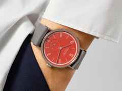 Nomos Glashütte Tangente 38 Datum "175 Years Watchmaking - Rambazamba" Handaufzug Edelstahl rotes Zifferblatt graues Textilband Glasboden – Herrenuhren Uhr mit Datum aus Edelstahl. Das Gehäuse ist rund und silber. Das Textilarmband ist grau. Das Zifferblatt ist arabisch Index und rot. – Ansicht 7