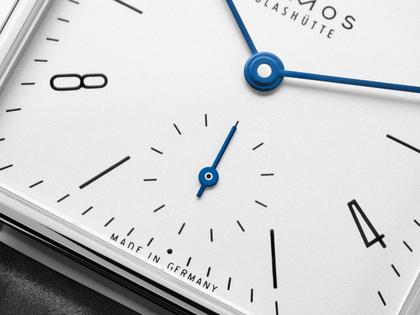 Nomos Glashütte Tetra 27 Weiss Handaufzug Edelstahl 27mm weißes Zifferblatt schwarzes Lederband Glasboden – Damenuhren Uhr ohne Datum aus Edelstahl und Leder. Das Gehäuse ist quadratisch und silber. Das Lederarmband ist schwarz. Das Zifferblatt ist arabisch Index und weiß. – Ansicht 3