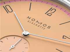 Nomos Glashütte Tangente 38 Datum "175 Years Watchmaking - Pastell" Handaufzug Edelstahl korallfarbenes Zifferblatt graues Textilband Glasboden – Herrenuhren Uhr mit Datum aus Edelstahl. Das Gehäuse ist rund und silber. Das Textilarmband ist grau. Das Zifferblatt ist arabisch Index und orange. – Ansicht 5