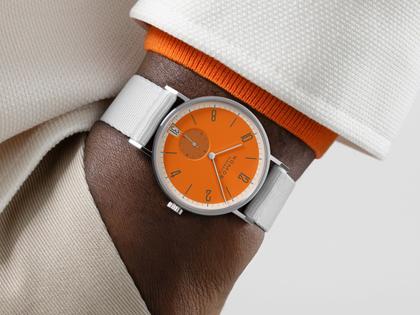 Nomos Glashütte Tangente 38 Datum "175 Years Watchmaking - Boje" Handaufzug Edelstahl orangenes Zifferblatt graues Textilband Glasboden – Herrenuhren Uhr mit Datum aus Edelstahl. Das Gehäuse ist rund und silber. Das Textilarmband ist grau. Das Zifferblatt ist arabisch Index und orange. – Ansicht 7