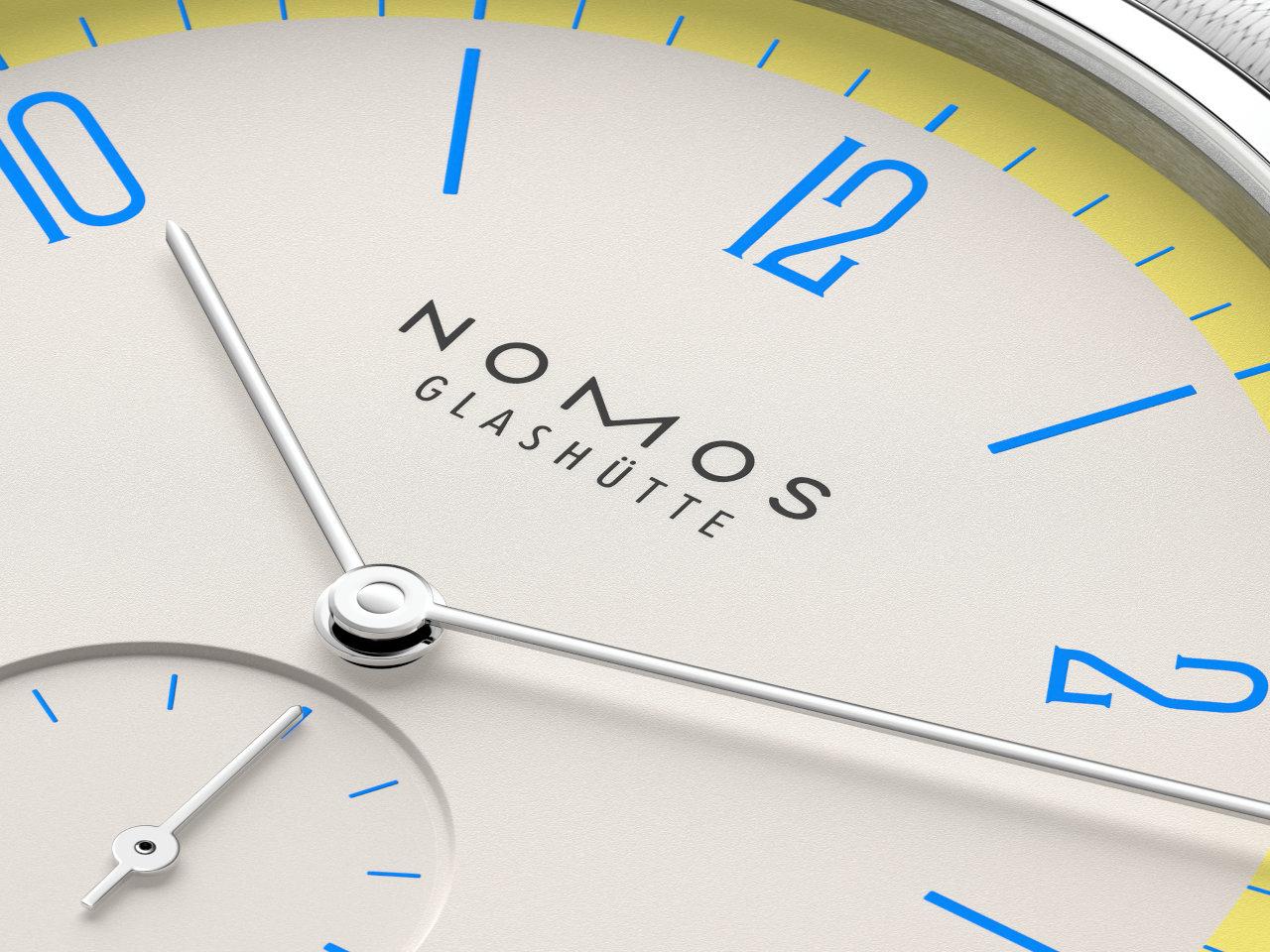 Nomos Glashütte Tangente 38 Datum "175 Years Watchmaking - Lemonbiscuit" Handaufzug Edelstahl cremeweißes Zifferblatt graues Textilband Glasboden – Herrenuhren Uhr mit Datum aus Edelstahl. Das Gehäuse ist rund und silber. Das Textilarmband ist grau. Das Zifferblatt ist arabisch Index und beige. – Ansicht 6