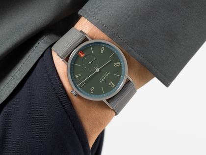 Nomos Glashütte Tangente 38 Datum "175 Years Watchmaking - Lakritze" Handaufzug Edelstahl graues Zifferblatt graues Textilband Glasboden – Herrenuhren Uhr mit Datum aus Edelstahl. Das Gehäuse ist rund und silber. Das Textilarmband ist grau. Das Zifferblatt ist arabisch Index und grau. – Ansicht 7