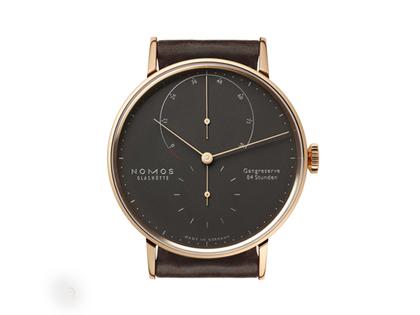 Nomos Glashütte Lambda 39 Samtschwarz Handaufzug Roségold 39mm schwarzes Zifferblatt braunes Lederband – Herrenuhren Uhr ohne Datum aus 750 Rotgold und Leder. Das Gehäuse ist rund und roségold. Das Lederarmband ist braun. Das Zifferblatt ist ein Index in schwarz. – Ansicht 2