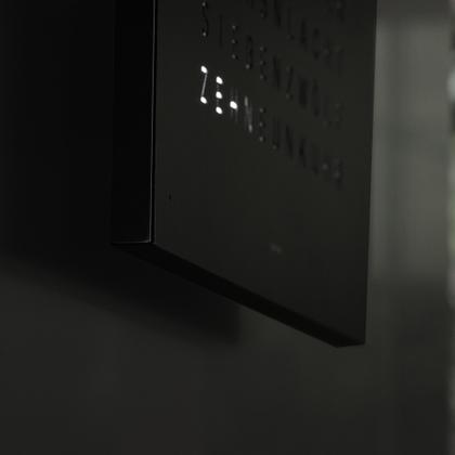Qlocktwo Earth 45 Black Pepper Monochrome Edition – Großuhren Wanduhr aus . Das Gehäuse ist quadratisch und schwarz. Das Zifferblatt ist digital und schwarz. – Ansicht 3