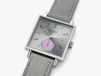 Nomos Glashütte Tetra Die Unerreichbare Handaufzug Edelstahl 29mm silberfarbenes Zifferblatt graues Veloursband Glasboden – Damenuhren Uhr ohne Datum aus Edelstahl und Leder. Das Gehäuse ist quadratisch und silber. Das Lederarmband ist grau. Das Zifferblatt ist arabisch Index und silber. – Ansicht 3