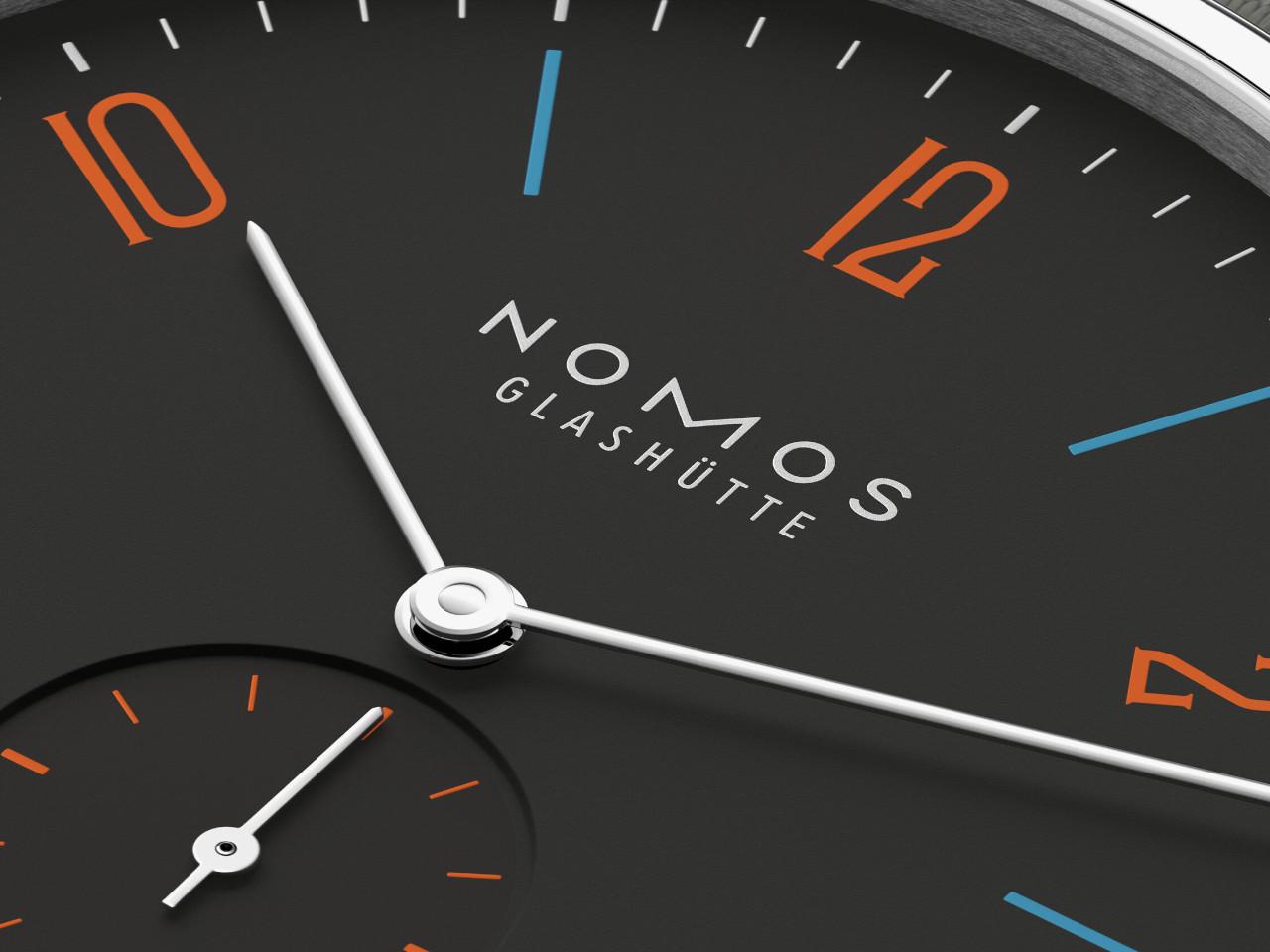 Nomos Glashütte Tangente 38 Datum "175 Years Watchmaking - Dunkelbunt" Handaufzug Edelstahl schwarzes Zifferblatt graues Textilband Glasboden – Herrenuhren Uhr mit Datum aus Edelstahl. Das Gehäuse ist rund und silber. Das Textilarmband ist grau. Das Zifferblatt ist arabisch Index und schwarz. – Ansicht 5