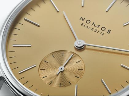 Nomos Glashütte Orion 33 Gold Handaufzug Edelstahl 33mm goldfarbenes Zifferblatt graues Lederband Glasboden – Damenuhren Uhr ohne Datum aus Edelstahl und Leder. Das Gehäuse ist rund und silber. Das Lederarmband ist beige. Das Zifferblatt ist ein Index in beige. – Ansicht 4