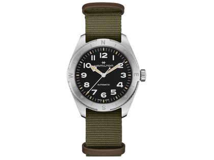 Herrenuhren Uhr ohne Datum aus Edelstahl. Das Gehäuse ist rund und silber. Das Textilarmband ist grün. Das Zifferblatt ist ein Index in schwarz.
