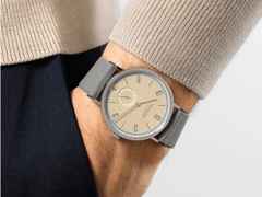 Nomos Glashütte Tangente 38 Datum "175 Years Watchmaking - Ariel" Handaufzug Edelstahl sandfarbenes Zifferblatt graues Textilband Glasboden – Herrenuhren Uhr mit Datum aus Edelstahl. Das Gehäuse ist rund und silber. Das Textilarmband ist grau. Das Zifferblatt ist arabisch Index und beige. – Ansicht 7