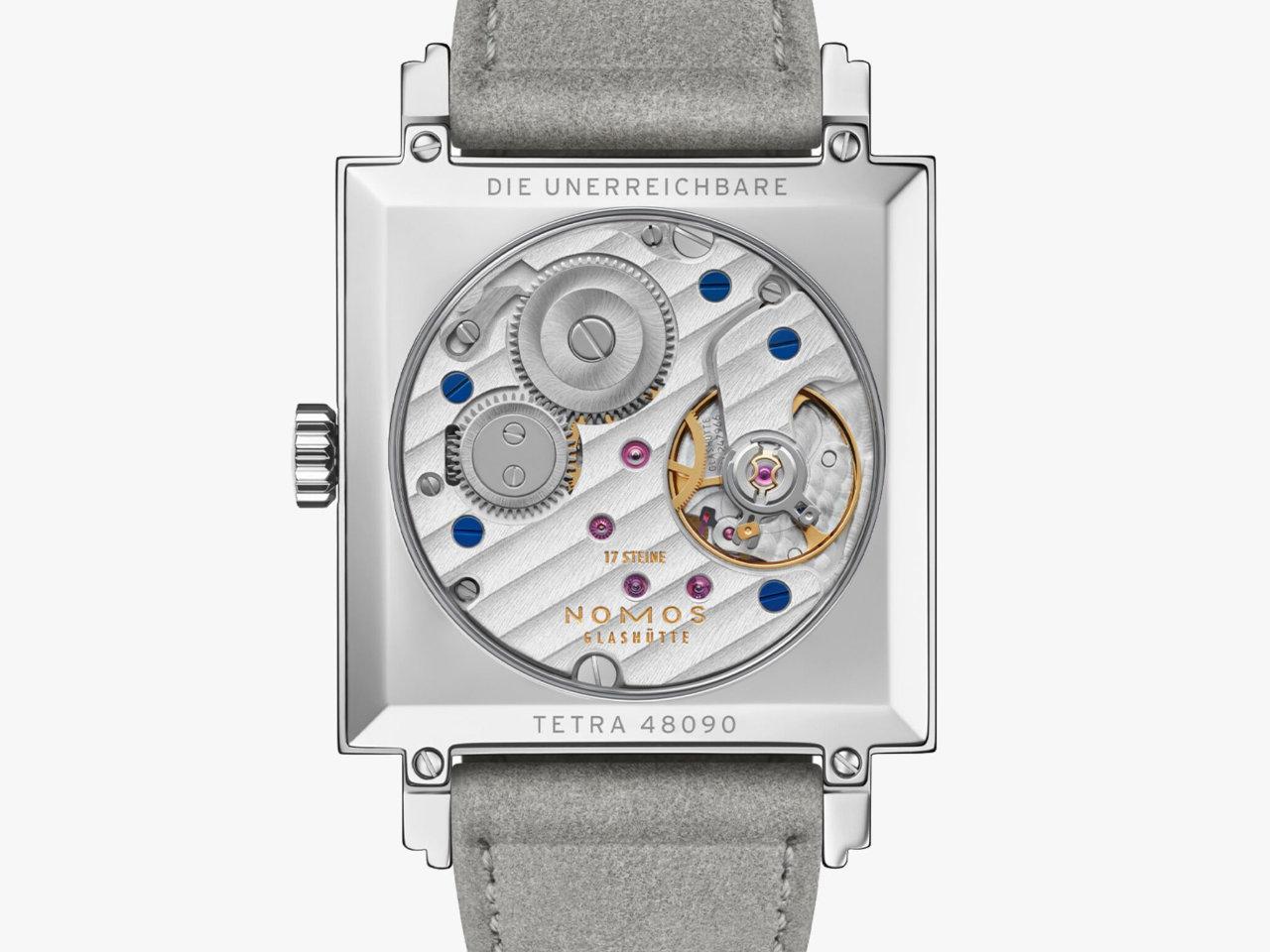 Nomos Glashütte Tetra Die Unerreichbare Handaufzug Edelstahl 29mm silberfarbenes Zifferblatt graues Veloursband Glasboden – Damenuhren Uhr ohne Datum aus Edelstahl und Leder. Das Gehäuse ist quadratisch und silber. Das Lederarmband ist grau. Das Zifferblatt ist arabisch Index und silber. – Ansicht 2