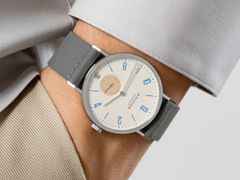 Nomos Glashütte Tangente 38 Datum "175 Years Watchmaking - Schulhausweiß" Handaufzug Edelstahl cremeweißes Zifferblatt graues Textilband Glasboden – Herrenuhren Uhr mit Datum aus Edelstahl. Das Gehäuse ist rund und silber. Das Textilarmband ist grau. Das Zifferblatt ist arabisch Index und beige. – Ansicht 7