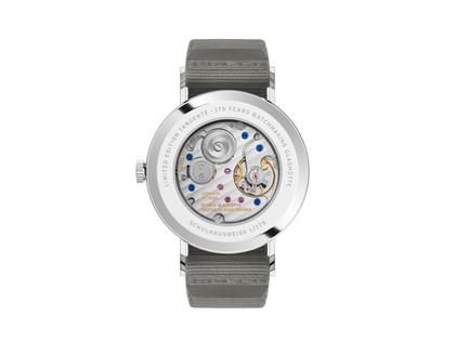 Nomos Glashütte Tangente 38 Datum "175 Years Watchmaking - Schulhausweiß" Handaufzug Edelstahl cremeweißes Zifferblatt graues Textilband Glasboden – Herrenuhren Uhr mit Datum aus Edelstahl. Das Gehäuse ist rund und silber. Das Textilarmband ist grau. Das Zifferblatt ist arabisch Index und beige. – Ansicht 2