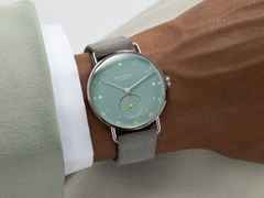 Nomos Glashütte Metro 33 Sage Handaufzug Edelstahl 33mm grünes Zifferblatt graues Lederband Glasboden – Damenuhren Uhr ohne Datum aus Edelstahl und Leder. Das Gehäuse ist rund und silber. Das Lederarmband ist grau. Das Zifferblatt ist ein Index in grün. – Ansicht 4