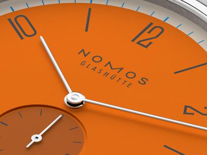 Nomos Glashütte Tangente 38 Datum "175 Years Watchmaking - Boje" Handaufzug Edelstahl orangenes Zifferblatt graues Textilband Glasboden – Herrenuhren Uhr mit Datum aus Edelstahl. Das Gehäuse ist rund und silber. Das Textilarmband ist grau. Das Zifferblatt ist arabisch Index und orange. – Ansicht 5