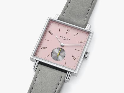 Nomos Glashütte Tetra Die Wildentschlossene Handaufzug Edelstahl 29mm rosafarbenes Zifferblatt graues Veloursband Glasboden – Damenuhren Uhr ohne Datum aus Edelstahl und Leder. Das Gehäuse ist quadratisch und silber. Das Lederarmband ist grau. Das Zifferblatt ist arabisch Index und rosa. – Ansicht 3